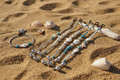 Lifestyle photo of turquoise sea turtle and starfish beaded bracelet and anklet on a sandy beach